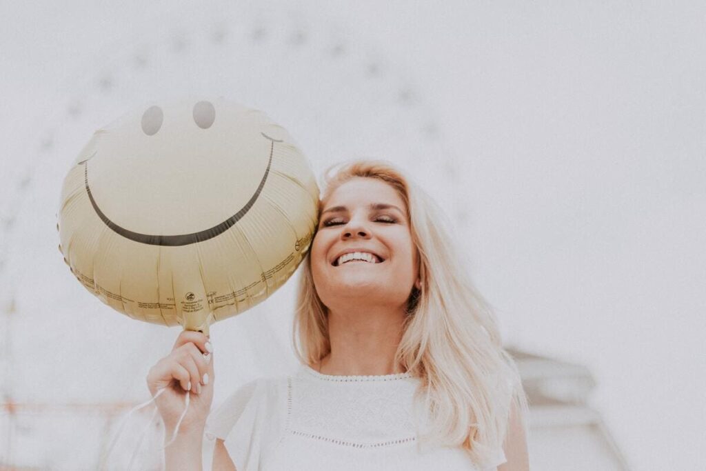 Mujer sonriendo con globo de emoticono feliz