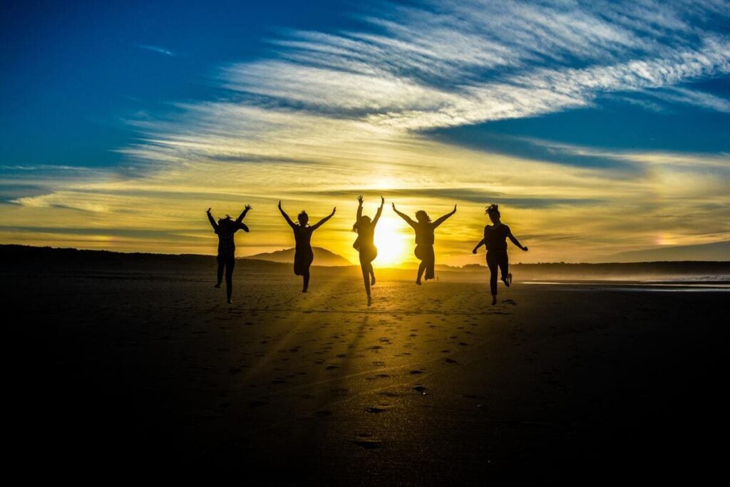 grupo de personas saltando en una playa al atardecer